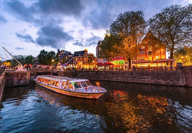 Avondfoto van een rondvaart met verlichte café's op de achtergrond